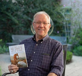 Thom Schmenk holding his book, Living Life 90 Days At A Time A Sarcoma Survivor's Journey